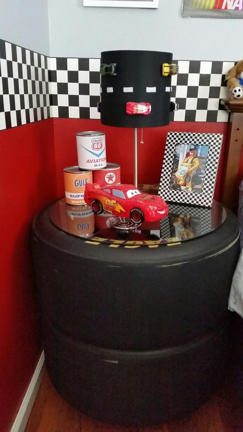 Night stand made from race car tires. Racing Decorations House, Race Car Playroom, Race Car Theme Room, Race Car Bathroom Ideas, Nascar Tire Ideas, Race Car Bedroom Decor, Cars Themed Bedroom Toddler, Nascar Bedroom Ideas, Boys Race Car Bedroom Ideas