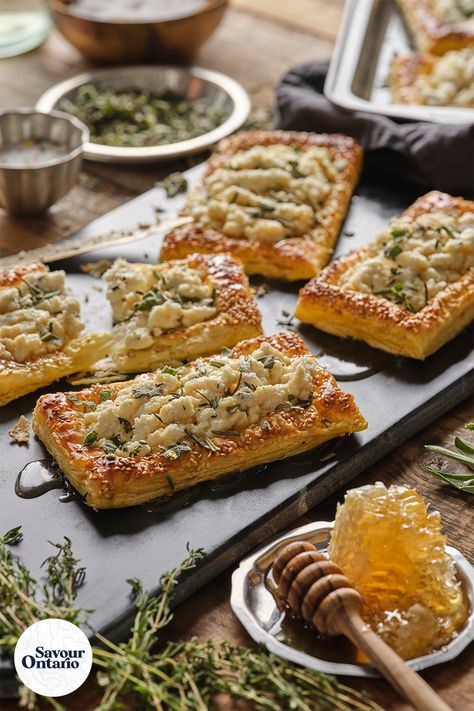 This Herbed Ricotta and Feta Puff Pastry Tart recipe, made with Ontario Ricotta and Feta cheese, is incredibly versatile and can be served up for any occasion. Notes of sweetness from the honey and puff pastry compliment the salty hits from the feta cheese with every bite. Let your imagination run wild and reap the rewards by topping these tarts with your favourite ingredients - like tomato, basil, and even roasted chicken - the sky’s the limit! Find this recipe and more at savourontario.ca! Puff Pastry With Ricotta Cheese, Ricotta Puff Pastry Recipes, Puff Pastry Ricotta Recipes, Puff Pastry Recipes Savory Tart, Puff Pastry Ricotta, Potato Puff Pastry, Ricotta Puff Pastry, Savoury Puff Pastry, Feta Pastry