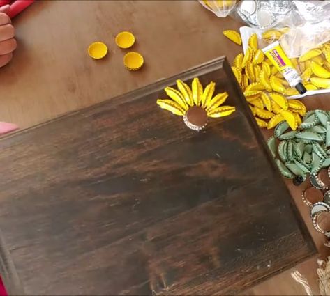 Easy To Make DIY Bottle Cap Sunflower Art American Flag Bottle Cap Art, How To Make Bottle Cap Flowers, Bottle Cap Art Diy, Bottle Cap Sunflower, Beer Bottle Cap Ideas, Sunflower Projects, Beer Cap Crafts Diy, Fence Board Crafts, Beer Bottle Cap Art