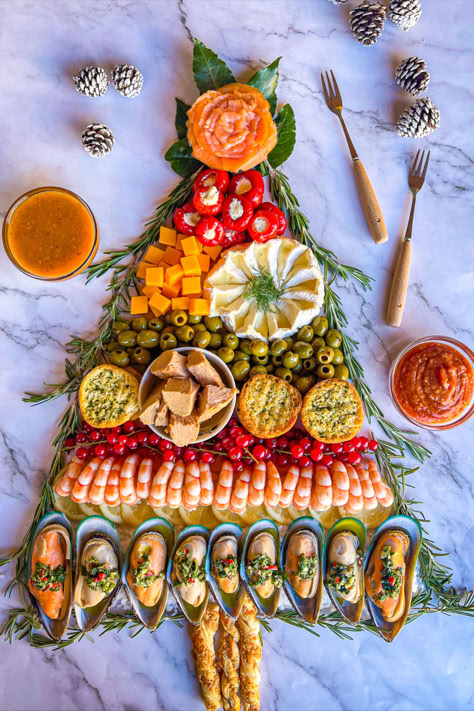 A seafood charcuterie board in the shape of a Christmas tree with sauces, utensils and wine glasses on the board around it. Christmas Seafood Platter, Caribbean Christmas Food, Fish Charcuterie Board, Smoked Salmon Charcuterie, Salmon Charcuterie Board, Salmon Charcuterie, Charcuterie Christmas Tree, Seafood Christmas, Christmas Seafood