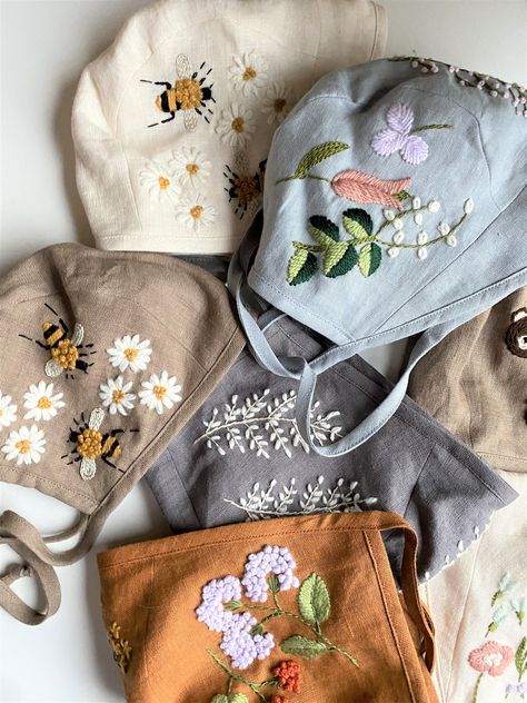 These sweet, hand embroidered baby bonnets are the work of a Latvian embroidery artist who sells her work on Etsy.  The fabric is linen and the bonnet is embroidered with wool thread. Just perfect for cool days to keep babies warms and then in Summer, to keep them cool.  Image courtesy of https://www.etsy.com/listing/620949454/linen-baby-bonnet-with-embroidered-fern Embroidered Fern, Mamma Bear, Mouth Mask Fashion, Mask Designs, Easy Face Mask Diy, Wool Embroidery, Baby Bonnets, Pola Sulam, Baby Bonnet