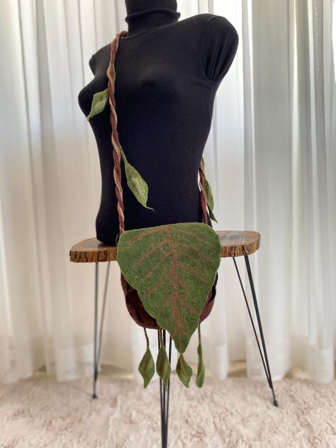 Inspired by nature, this unique bag can make you feel the magic in the depths of the forest.  Felted from wool, the main body of this bag resembles a 3-dimensional tree bark, the flap is a large green leaf and the shoulder strap is a leafy vine.  It can be used as a shoulder bag or crossbody bag.  Complete your festival costume with this unique bag. It is spacious enough to carry your magic bottles, runes, tarot cards and more.  The swaying leaves on the handle and bottom of the bag dance in the wind :)  Magnetic snap closure on the inside.  Measurements;   Height; 8 inches - 21 cm Width ; 7.5 inches - 19 cm Strap; 49.5 inches - 126 cm If you have any questions, you can write me a message. Leaf Bag Diy, Leaf Clothes, Druid Witch, Leaf Bag, Fairytale Forest, Tree Bag, Festival Costume, Magic Bottles, Ren Fest