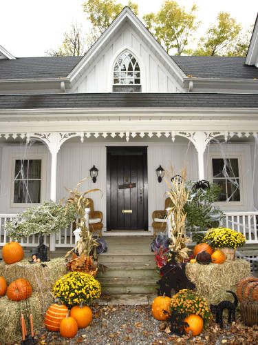 Create a classic country vignette on your front porch for Halloween by arranging hay bales, mums, pumpkins, and dried corn stalks around your steps. Fake spiderwebs add a not-too-scary touch. Spooky Outdoor Halloween Decor, Halloween Vignette, Diy Halloween Dekoration, Halloween Outdoor Decoration, Dekorasi Halloween, Country Halloween, Halloween Diy Outdoor, Halloween Front Porch Decor, Halloween Decorations Diy Outdoor