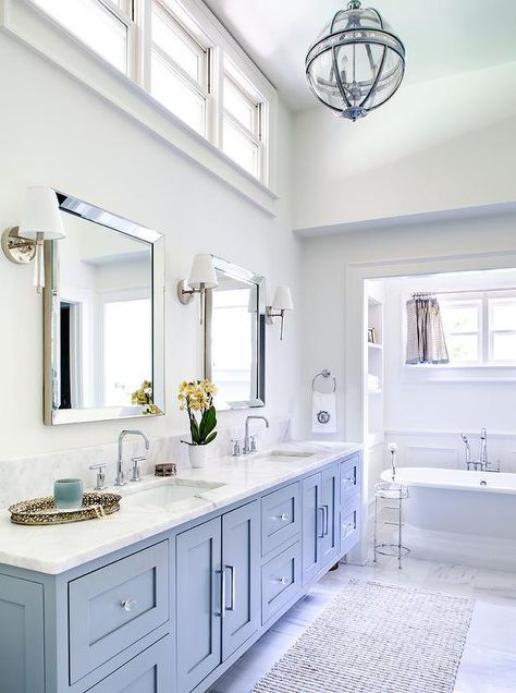 Located under a high ceiling, clerestory windows are positioned over beveled vanity mirrors lit by nickel and glass sconces. White And Tan Bathroom, Tan Bathroom, Ceiling Bathroom, Cheap Bathroom Remodel, Cabinets Design, Large Bathroom, Cheap Bathrooms, Diy Ceiling, Transitional Bathroom