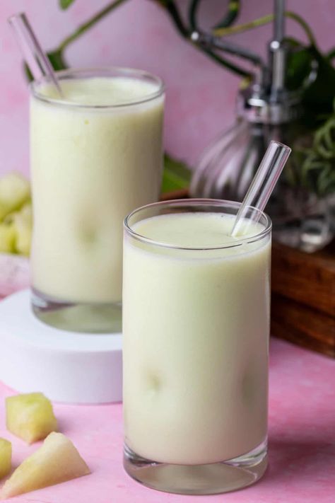 Two glasses of honeydew smoothie are on a pink background with plants in the background. Blueberry Raspberry Smoothie, Honeydew Melon Smoothie, Smoothie Without Milk, Zesty Salad Dressing, Honeydew Smoothie, Banana Oatmeal Bars, Strawberry Blueberry Smoothie, Melon Smoothie, Refreshing Smoothies