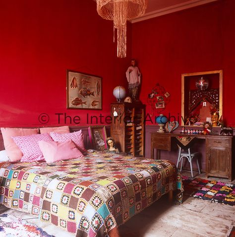 Montpellier - A bold red bedroom with a double bed with a patchwork quilt and pink cushions. A wooden desk and chair stand against one wall. Red Bedroom, Desk And Chair, Red Bedding, Bedroom Red, Pink Cushions, Monochrome Color, Red Rooms, The Apartment, Wooden Desk