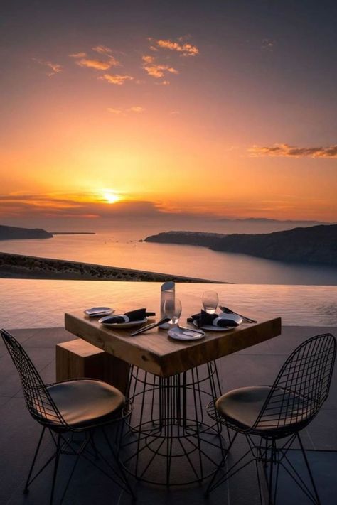 A table with 2 chairs. In the background we see the sun setting creating beautiful colors in the sky Greek Vacation, Eastern Mediterranean, Honeymoon Spots, Modern Deco, Alaska Travel, Dream Holiday, Beautiful Places To Travel, Relax Time, Infinity Pool