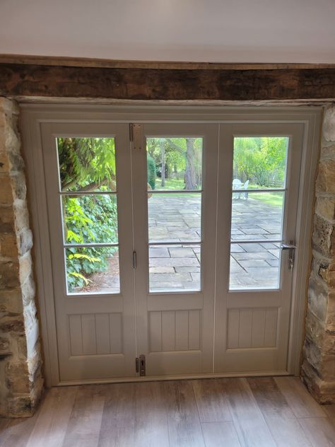 White bi-fold doors in a conservatory. The door is closed with a view out onto a large garden. Bifold Doors With Windows, Timber Bifold Doors, Bifold Doors Kitchen, Bifold Doors Extension, Bifold Garage Doors, White Bifold Doors, Bifold French Doors, Wooden Bifold Doors, Summer House Interiors