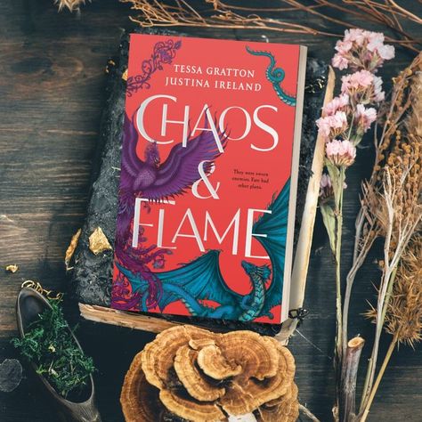 A dark wooden table with dried flowers and mushrooms and the book Chaos & Flame by Tessa Gratton and Justina Ireland Ancient Magic, Ya Fantasy, She Knows, Book Tv, Two People, Free Books, To Win, New Books, Two By Two