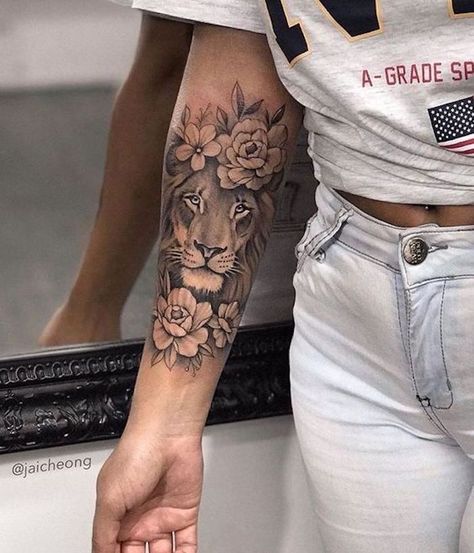 woman-wearing-white-jeans-grey-shirt-lion-tattoo-on-arm-forearm-tattoo-of-lion-head-surrounded-by-flowers Womens Tattoos Arm, Lion Tattoo Girls, Girl Arm Tattoos, Cool Arm Tattoos, Leo Tattoos, Inspiration Tattoos, Forearm Tattoo Women, Arm Sleeve Tattoos, Best Sleeve Tattoos