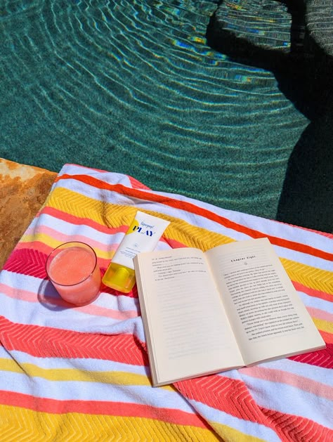 A bright colored towel sitting by the pool. A pink grapefruit drink, sunscreen, and an open book are on the towel Summer Colorful Aesthetic, Fresh Summer, Vibrant Summer Aesthetic, Summer Vsco Aesthetic, Summer Bright Aesthetic, July Summer Aesthetic, Summer Day Aesthetic, Colorful Summer Aesthetic, Summertime Aesthetic