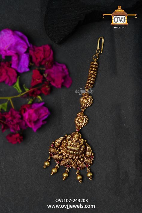 OVJ's exquisite antique gold maang tikka designs are a firm favourite among jewellery connoisseurs across generations. This south indian maang tikka gold jewellery enchants with spiritually charged peacocks and goddess lakshmi motifs and is bedecked with kemp stones.  View  latest antique maang tikka jewellery  designs at OVJ website and shop, one of the best jewellery shops in Dindigul. Temple Maang Tikka, Antique Maang Tikka Gold, Nethi Chutti Designs Gold, Papadi Billa Designs Gold Latest, South Indian Maang Tikka, Maang Tikka Bridal Gold, Mangtika Jewellery Gold, Gold Tikka Jewelry, Gold Maang Tikka Designs