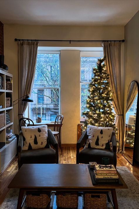 cozy warmly lit apartment, photo facing open window with brownstone view. lit Christmas tree, green chairs, holiday theme Nyc Apartment Modern, New York Apartment Aesthetic Interior, Nyc Aesthetic Apartment, Aesthetic Nyc Apartment, New York Apartment Aesthetic, Nyc Apartment Aesthetic, Winter Apartment, Cozy Apartment Aesthetic, Apartment New York