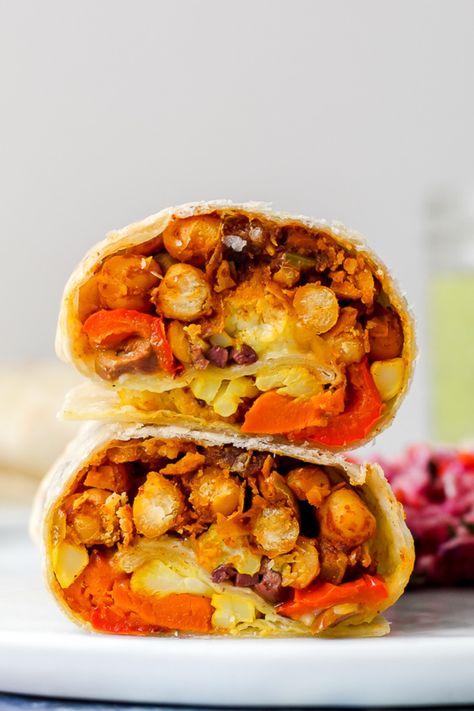 Moroccan chickpea burritos feature Moroccan-spiced chickpeas, turmeric-roasted cauliflower, roasted sweet potatoes, and peppers, feta, and olives. The dipping sauce is a tahini, lemon, and herb sauce- it's a delicious vegetarian dinner that is nutrient-rich and super flavourful! Green Tahini Sauce, Chickpeas Roasted, Green Tahini, Moroccan Chickpea, Moroccan Vegetables, Spiced Chickpeas, Burritos Recipe, Roasted Vegetable, Tahini Sauce