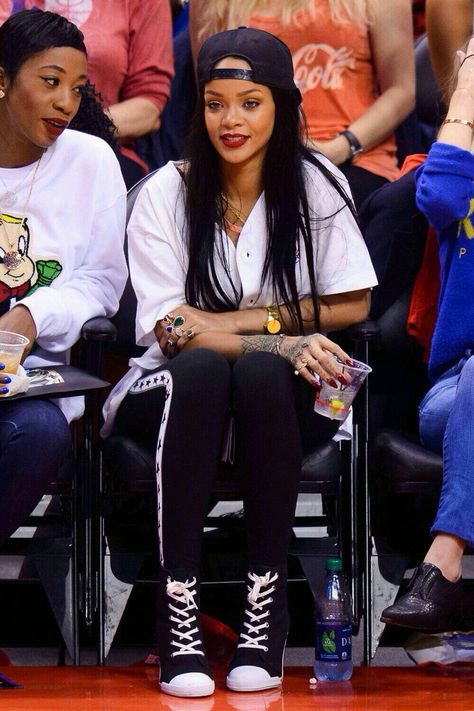 Rihanna rocks a backwards cap while attending a Clippers basketball game during the 2014 NBA Playoffs at Staples Center on Friday (May 9) in Los Angeles. The 26-year-old entertainer sat next to her BFF Melissa Forde while cheering on the Clippers, who lost to the Oklahoma City Thunder by a final score of 118-112. Rihanna Snapback, Look Hip Hop, Rihanna Cover, Basketball Game Outfit, Cultura Hip Hop, Fashion 23, Looks Rihanna, Rihanna Love, Rihanna Outfits