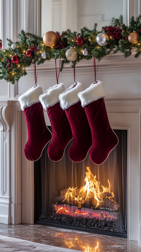 Three burgundy velvet Christmas stockings with white fur trim hang from a fireplace, surrounded by festive decor and a warm Red White Christmas Decor, Red Velvet Christmas Stocking, Red And White Christmas Decor, Velvet Christmas Stocking, White Christmas Decor Ideas, Cozy Table, Wedding Fireplace, Red Velvet Christmas, Elegant Ornaments