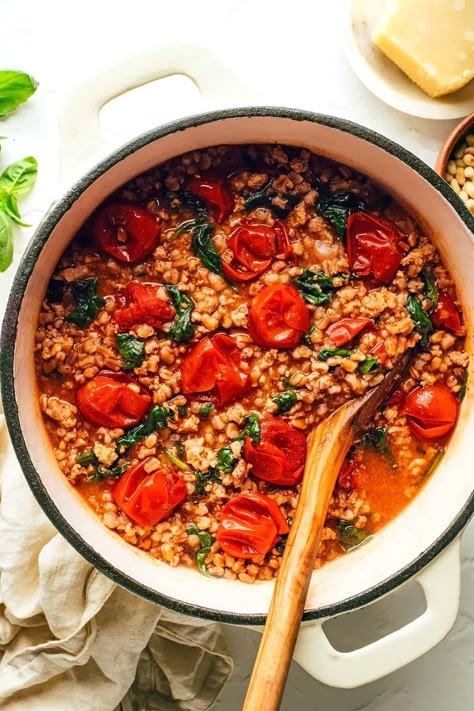 This one pot farro recipe is slow-simmered with Italian sausage, cherry tomatoes, fresh basil, garlic, spinach and finished with a sprinkling of pine nuts and Parmesan. Such an easy dinner recipe and always SO delicious. Feel free to use plant-based sausage to make it vegetarian too! | gimmesomeoven.com Farro Recipes, Garlic Spinach, Parmesan Rind, Ground Italian Sausage, Gimme Some Oven, Veggie Stock, Smitten Kitchen, Pine Nuts, Italian Sausage