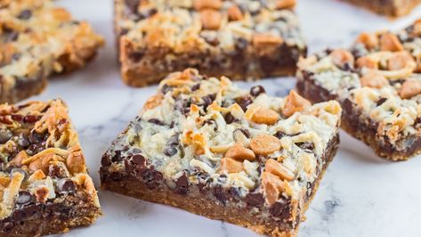 If you're craving an ooey, gooey cookie bar that's reminiscent of your childhood, this 7-layer cookie bar recipe totally delivers. It's also super easy to make! 7 Layer Cookies, Dolly Bars, Christmas Party Snacks, Magic Cookie Bars, Caramel Bits, Gooey Cookies, Chocolate Graham Crackers, Cookie Bar, 7 Layer