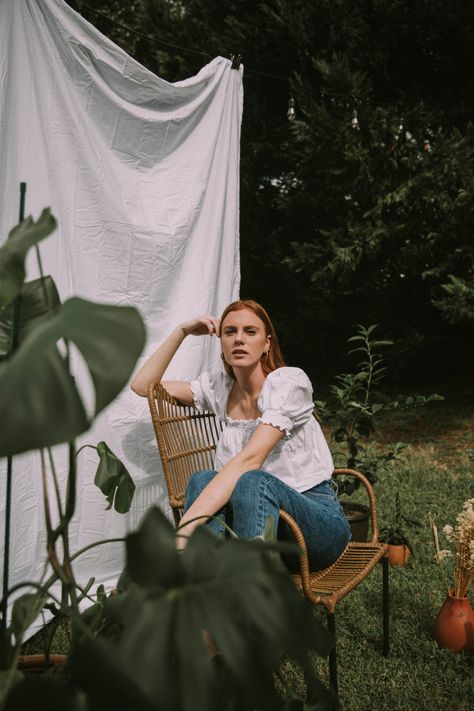 A red headed girl sitting in a chair for a backyard photoshoot with a bed sheet as the backdrop. Backyard Portrait Ideas, Home Garden Photoshoot Ideas, Hanging Sheets Photoshoot, Yard Photoshoot Ideas, Bed Sheet Backdrop Photography, Bed Sheets Photoshoot, Porch Photoshoot Picture Ideas, Outdoor Couch Photoshoot, Outdoor Sheet Photoshoot