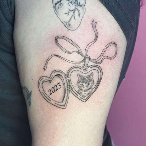 Heart locket ft. Bean 🥺 the cutest little cat 🐱💕 . . . . Tattooed @havenstudionyc. Currently booking June & July . . . . . . . . . #lockettattoo #cattattoo #catlovers #finelinetattoo #finelinetattooartist #nyctattooer #nyctattooartists #ladytattooers #cutetattoo #femaletattooartist #newyorkcity #femininetattoos #delicatetattoos #cutecat #petportraittattoo #catstagram #brooklyn #tattooartistbrooklyn Cat Heart Locket Tattoo, Pretty Cat Tattoos, Custom Cat Tattoo, Heart Shaped Locket Tattoo, Dog Locket Tattoo, Cat Pet Tattoo, Pet Locket Tattoo, Cat Locket Tattoo, Open Locket Tattoo