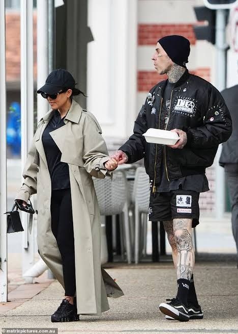 Kourtney Kardashian and Travis Barker HOLD hands in Brisbane after enjoying lunch at vegan hotspot Dicki's Travis Barker 90s, Travis Barker Style, Travis Barker And Kourtney Kardashian, Kourtney Kardashian And Travis Barker, Kourtney Kardashian And Travis, Kardashian Fashion, Yankees Cap, Man Outfit, Tan Trench Coat