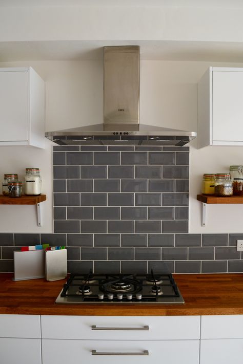 Grey metro tiles with AEG gas hob and extractor fan #grey gray #metro #tiles #hob #kitchen #shelves #Benchmarx #Benchmarxkitchen #josephjoseph #AEG #extractorfan #gashob #oakworktop Tiled Splashback Cooker, Cooker Splashback Ideas Tiles, Hob Extractor Fan Ideas, Hob Backsplash Ideas, Grey Kitchen Tiles Wall, Grey Metro Tiles Kitchen, Grey Kitchen Splashback Ideas, Kitchen Hob Ideas, Grey Tiles Kitchen