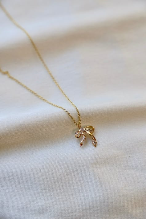 This CZ Bow Necklace features a bow pendant charm detailed with cz's for a timeless and elegant look. The perfect accessory to add a sweet and delicate, yet eye-catching touch to your look. Materials: Gold filled chain, gold plated and cubic zirconia charm Length: 16"-18" adjustable SKU: CN1546G Cheap White Dainty Charm Necklaces, Gold Necklace With Charm, Cheap Dainty White Charm Necklaces, Luxury Dainty Jewelry Gift, Cute Girly Jewelry, Gold Bow Necklace, Dainty Gold Jewelry Aesthetic, Simple Elegant Jewelry, Cute Jewellery