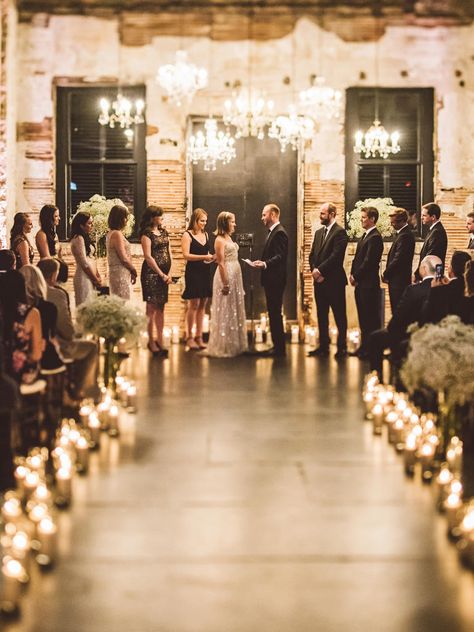 Set the tone of an industrial wedding space with moody lighting highlighting chandelier and candle-lit displays for a twilight gleam. Candle Light Ceremony Wedding, Candle Lit Wedding Ceremony Outdoor, Candle Ceremony Wedding, Candle Lit Wedding Alter, Candle Lit Wedding Aisle, Candle Aisle, Candle Lit Isle, Candle Lit Alter Wedding Ceremonies, Wedding Ceremony Altar