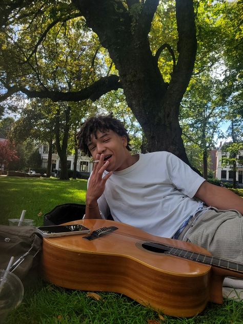 Boy with guitar sitting in grass smoking sigarette. In the park with sun laughing. Boy With Guitar, The Park, Guitar, Sun, Quick Saves