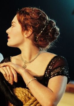 During the beloved dinner and third class dance scenes in Titanic, Rose, played by Kate Winslet, wears a lovely yet simple headband. This headband is long strip with jewels that spaced apart and wraps around her head and into her hair. It gives her almost ethereal look that is also sophisticated. Titanic Fashion, Roman Hair, Titanic Kate Winslet, Dead Bride, Times Of The Day, Simple Headbands, The Phantom Of The Opera, Curly Hair Styles Easy, Hair Adornments