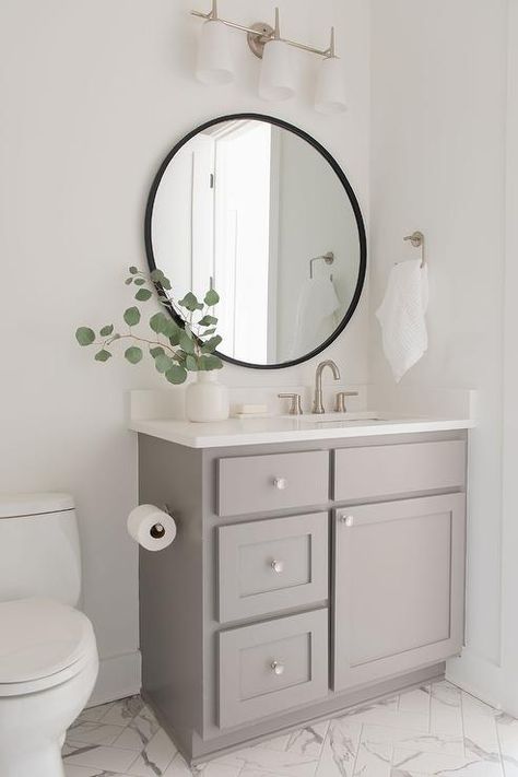 Round black mirror above a gray single washstand fitted with a white quartz countertop and a satin nickel faucet in a transitional bathroom. Cabinet Repainting, Modern Master Suite, Makeover Kamar Mandi, Nickel Faucet, Dining Room Renovation, Desert Boho, Transitional Bathroom, White Oak Floors, Hall Bathroom