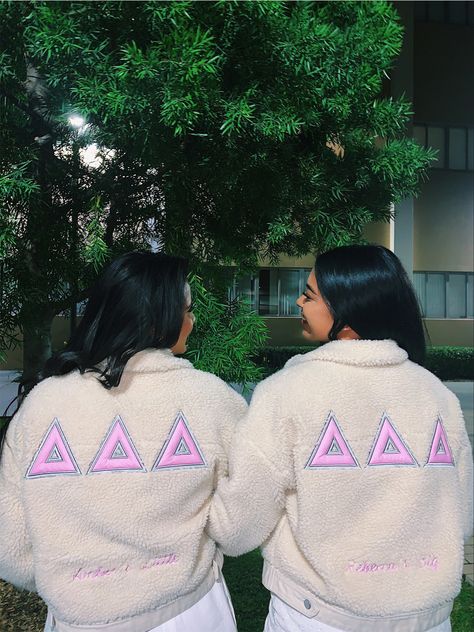 Two girls with their backs facing the camera. They are wearing white jackets with 3 pinks deltas while looking at eachother. Sorority Jackets Ideas, Tri Delta Merch, Sorority Jackets, Theta Merch, Aphi Merch, Paddle Ideas, Big Little Basket, Delta Delta Delta, Meeting Outfit