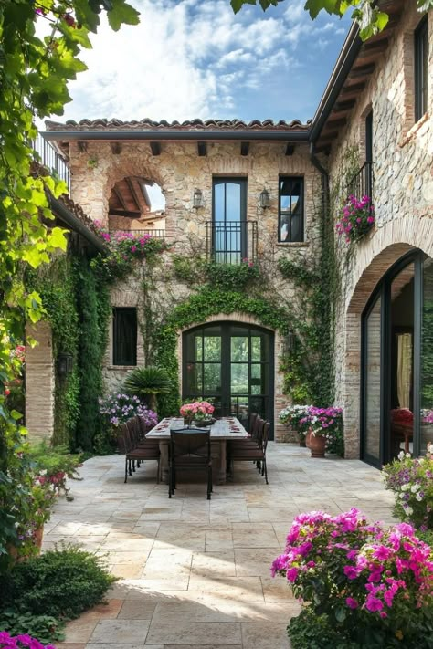 New tuscan house courtyard with flowers and dining area. Discover the timeless charm, design features, and cozy allure of Tuscan houses. Tuscan Villa Exterior, Tuscan Backyard, Tuscan Patio, Tuscan Houses, Tuscan Courtyard, Italian Style Home, Tuscany Home, House Courtyard, Italian Living