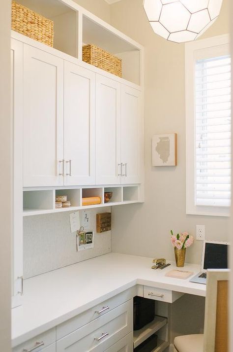 A white built-in l-shaped desk is accented with nickel pulls and a white quartz countertop and is positioned beneath a white cork board fixed beneath white shaker cabinets flanked by open shelving. Built In L Shaped Desk, Home Office With Couch, Den Library, Transitional Home Office, Home Office Cabinets, Library Office, Office Remodel, Office Nook, Office Couch