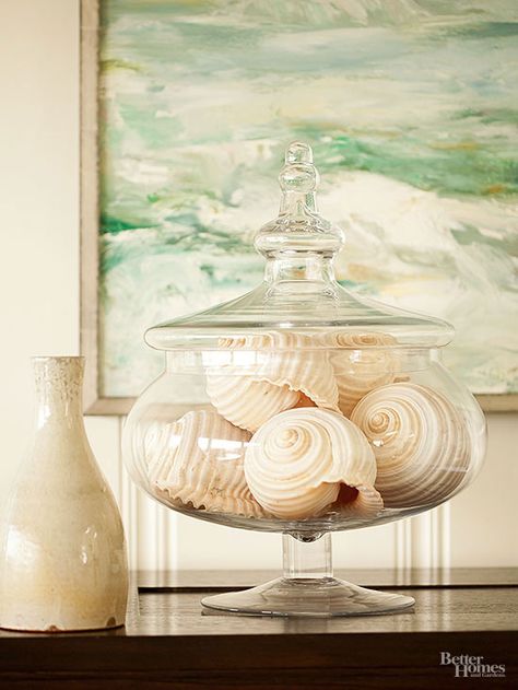 Maximize neutral hues in your home by decorating with nature. Filling a glass bowl with stones, shells or pinecones is an easy (and affordable) way to put nature on display. Shallow Glass Bowl Decor Ideas, Shell Display Ideas Jars, Seashell Jar Display, Decorating With Nature, How To Showcase Seashells, Shells In Glass Jars Display, Sea Shell Jar, Glass Bowl Decor, Seashell Display