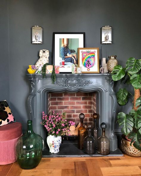 Layer artwork, houseplants and decor for a maximalist look. Quirky Mantle Decor, Mantel Decorating Ideas Maximalist, Maximalist Decor Fireplace, Witchy Mantel Decor, Mantle Decor Maximalist, Maximalist Fireplace Decor, Eclectic Fireplace Mantle Decor, Maximalist Fireplace Mantle, Eclectic Mantel Decor