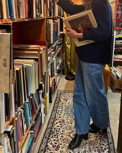 girl in blue jeans, blue sweater, and black boots with long brown hair looking at a bookcase full of old books in a cozy bookstore. bookstore full of pretty vintage books. cozy winter aesthetic. fall reading aesthetic. English Autumn Outfits, Cozy Pictures Aesthetic, Bookseller Aesthetic Outfit, Autumn Manifestation, Winter Vision Board, Indie Fall Outfits, Autumn Cozy Aesthetic, Fall Aesthetic Instagram, Library Clothes