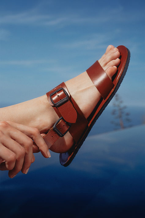 A young woman sits beside a swimming pool with her feet in the water. Next to her, a pair of Groundies Kos sandals in cognac. Unisex Sandals, Barefoot Sandal, Weather Activities, Get Ready For Summer, Men Fashion Casual Outfits, Sandals Brands, Men Fashion, Summer Style, Get Ready