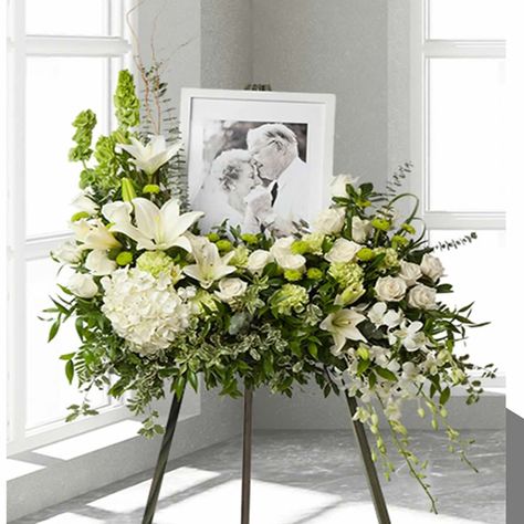 The precious moments spent with loved ones are the moments we want to hold onto forever. Capture this sentiment with a timeless display of all white.  This spray is crafted with artistry by our expert florists with hydrangea, roses, button poms, dendrobium orchids, lilies, carnations Bells of Ireland accented with lush greens,  Personalize this remembrance with your favorite picture of your loved one.   It make this an unforgettable way to commemorate a lifetime of shared loving experiences.Will Memory Table For Celebration Of Life, Memorial Service Flower Arrangements, Celebration Of Life Floral Arrangements, Memorial Arrangements, Memorial Decor, Tiny Bouquet, Frame Arrangement, Bells Of Ireland, Floral Design Business