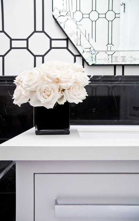 A black vase contrasted with white roses sits on a white quartz countertop accenting a white washstand positioned against black marble wainscoting. White Vanity Mirror, Gray Shower Tile, Marble House, Vase Noir, Elegant Interior Design, Vase White, Quartz Countertop, White Quartz Countertop, Black Vase