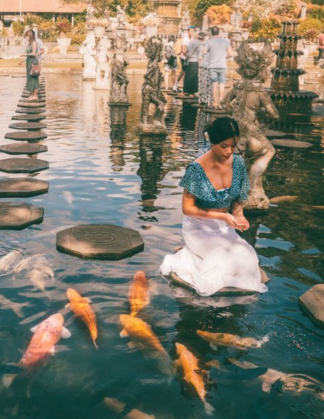 a girl feeding koi fish in a pond at a balinese temple called tirta gangga in bali Tirta Gangga Bali, Temple Bali, Bali Guide, Solo Travel Destinations, Koi Fish Pond, Solo Travel Tips, Fish Pond, Koi Pond, Bali Travel