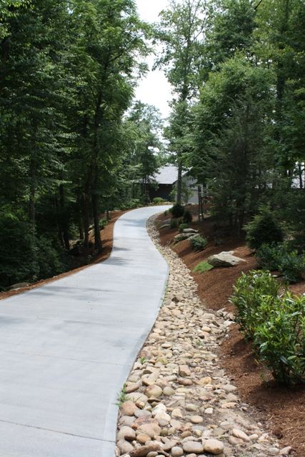 Landscape Beside Driveway, Rocks Lining Driveway, Landscaping By Road, Landscaping A Long Driveway, Driveway Entrance Landscaping Entryway Front Yards, Hill Driveway Ideas, Steep Driveway Landscaping, Steep Hill Driveway Ideas, Driveway On A Slope