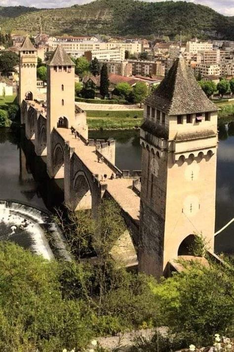 The Pont Valentré is a medieval bridge located in Cahors, France, renowned for its impressive architecture and historical significance. Built in 14th Century, this fortified bridge spans the Lot River and features three striking towers with defensive purposes, making it both a functional and aesthetic marvel of its time. Castles Medieval, Medieval Bridge, Aesthetic Marvel, Town Building, Medieval Houses, Environmental Design, Medieval Town, Cool Landscapes, Medieval Castle