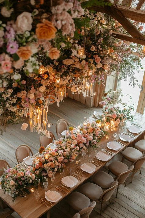 Elegant wedding table with lush floral arrangements and chandeliers. Unleash your inner florist with wild and whimsical floral wedding ideas that will make your special day bloom like never before. Elegant And Whimsical Wedding, Dreamy Wedding Decoration, Moody Garden Party Wedding, Bold Wedding Florals, Spring Florals Wedding, Floral Reception Decor, Floral Wedding Table Decor, 2025 Pantone, Whimsical Floral Wedding