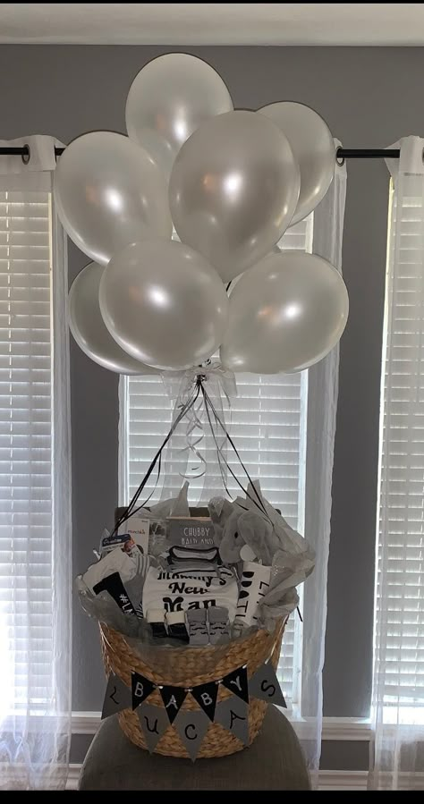 This turned out so cute! Color scheme is grey, black and white with lots of different boy goodies and necessities, with the hand written banner across the front. The balloons are intended to be cloud like with white and grey but the grey blends a little too much although I still loved it. White Color Theme Party Basket, White Color Basket Party Ideas, Gift Basket Baby Shower Boy, Grey Gift Basket Ideas, Baby Shower Boy Gifts Basket, Black And White Gift Basket Ideas, Baby Gift Basket Ideas For Boys, Baby Shower Hanger Basket