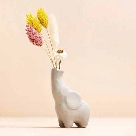 A mini ceramic grey vase shaped like an elephant  	Super small in size to fit a single stem or mini posy  	Simply pop the florals in the elephant's trunk  	Perfect for gifting to a lover of animals      Please note the intended use of this vase is for a single stem or posy and is not suitable for water.   Product Information    This adorable little bud vase will fit your favourite mini posy or single stem with pride.     Made of ceramic, this tiny elephant is stood with its trunk in the air, eye Air Dry Clay Elephant, Bud Vase Ceramic, Clay Animals Sculpture, Clay Vase Ideas, Elephant Clay, Ceramics Gifts, Ceramic Gift Ideas, Mini Ceramics, Animal Vase