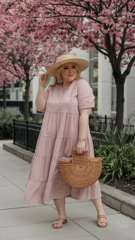 In this lovely photograph, a plus-size model embodies the essence of spring in a charming pink tiered dress, enhanced by delicate polka dots that add a playful touch. The dress flows gracefully, making it an ideal choice for various occasions, from garden parties to leisurely brunches. Paired with a wide-brimmed straw hat and a stylish woven bag, this outfit radiates a relaxed yet chic vibe perfect for warm weather. The sandals provide comfort while keeping the look effortlessly elegant. This en Pink Tiered Dress, Plus Size Spring Outfits, Wide Brim Straw Hat, Plus Size Spring, Spring Vibes, Garden Parties, Woven Bag, Tiered Dress, Wide Brimmed