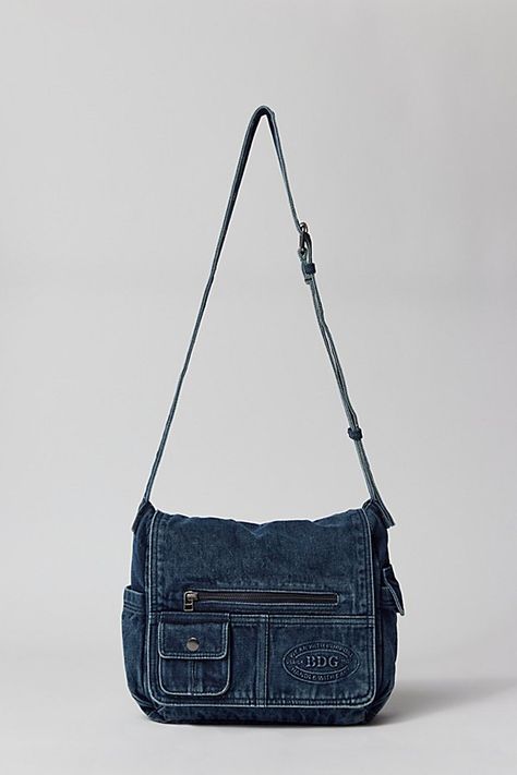 Essential messenger bag crafted from premium BDG denim. Low-profile silhouette with a pocketed flap closure. Lined interior with two pockets and plenty of space for your essentials. Complete with a zip pocket at the back for easy access, plus a water bottle pocket at the side. Finished with an adjustable strap - wear it on your shoulder or crossbody. Urban Outfitters exclusive. Features BDG denim messenger bag Washed soft denim with tons of storage Plenty of pockets inside and out Water bottle p School Satchel Bag, Denim Satchel Bag, Cute Vintage Bags, Messenger Crochet Bag, What’s In My Messenger Bag, Cute Everyday Bags, Denim Purses And Bags Old Jeans, Grunge Messenger Bag, Cute Bags For School