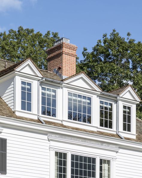 The renovated attic has a large dormer with three pedimented roofs. #brickchimney #cedarshingleroof #clapboardsiding #casementwindows #dormer #sheddormer #pedimenteddormers #colonialarchitecture #classicaldesign #traditionalarchitecture Renovated Attic, Large Dormer, Dormer Addition, Small House Renovation, Cape Cod House Exterior, Craftsman Remodel, Dormer Roof, Window Remodel, Cedar Shingle Roof