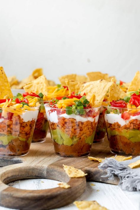 This Seven Layer Bean Dip made in individual cups is the ultimate party appetizer. They are so easy to make, everyone always loves them, and the Mexican rice is a special touch! Serve with your favorite chips and enjoy! #sevenlayerbeandip #partyappetizer #appetizerideas #easyappetizers #beandip #individualappetizers Fiesta Party Appetizers, Chips And Dips Appetizers, Chips And Dip Display Serving Ideas, Chips Set Up For Party, Individual Nacho Cups, Chips And Dip Bar, Chips And Dip Party Display, Chips And Salsa Bar Wedding, Seven Layer Bean Dip